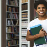 Handsome african american male student posing in campus library, empty space